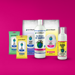 A set of earthbath branded pet grooming products for cats on a pink background